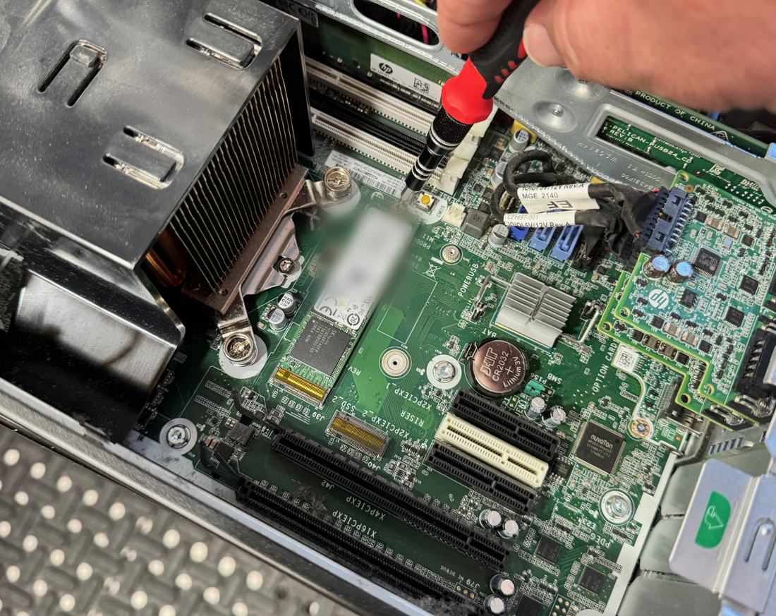 M.2 NVMe SSD seated in the motherboard M.2 slot of an HP small form factor desktop, with a screwdriver on the retaining screw
