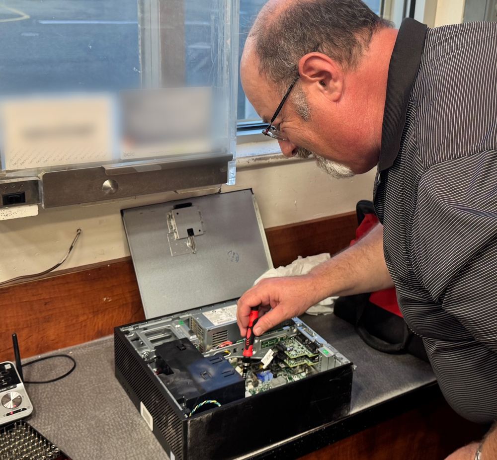 Computer technician removing the drive from a small form factor desktop PC on a retail counter